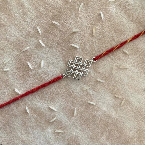 An Eternity Knot Silver Rakhi With Red Moli Thread